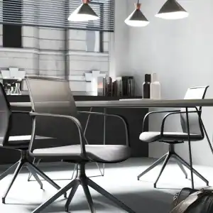 grey mesh back and seat pad chair, with black frame, hoop arms and pyramid style legs with castors by a table